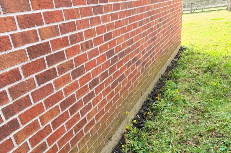 After-treatment termite trench around a brick home slab in Daphne Alabama, illustrating ongoing termite protection