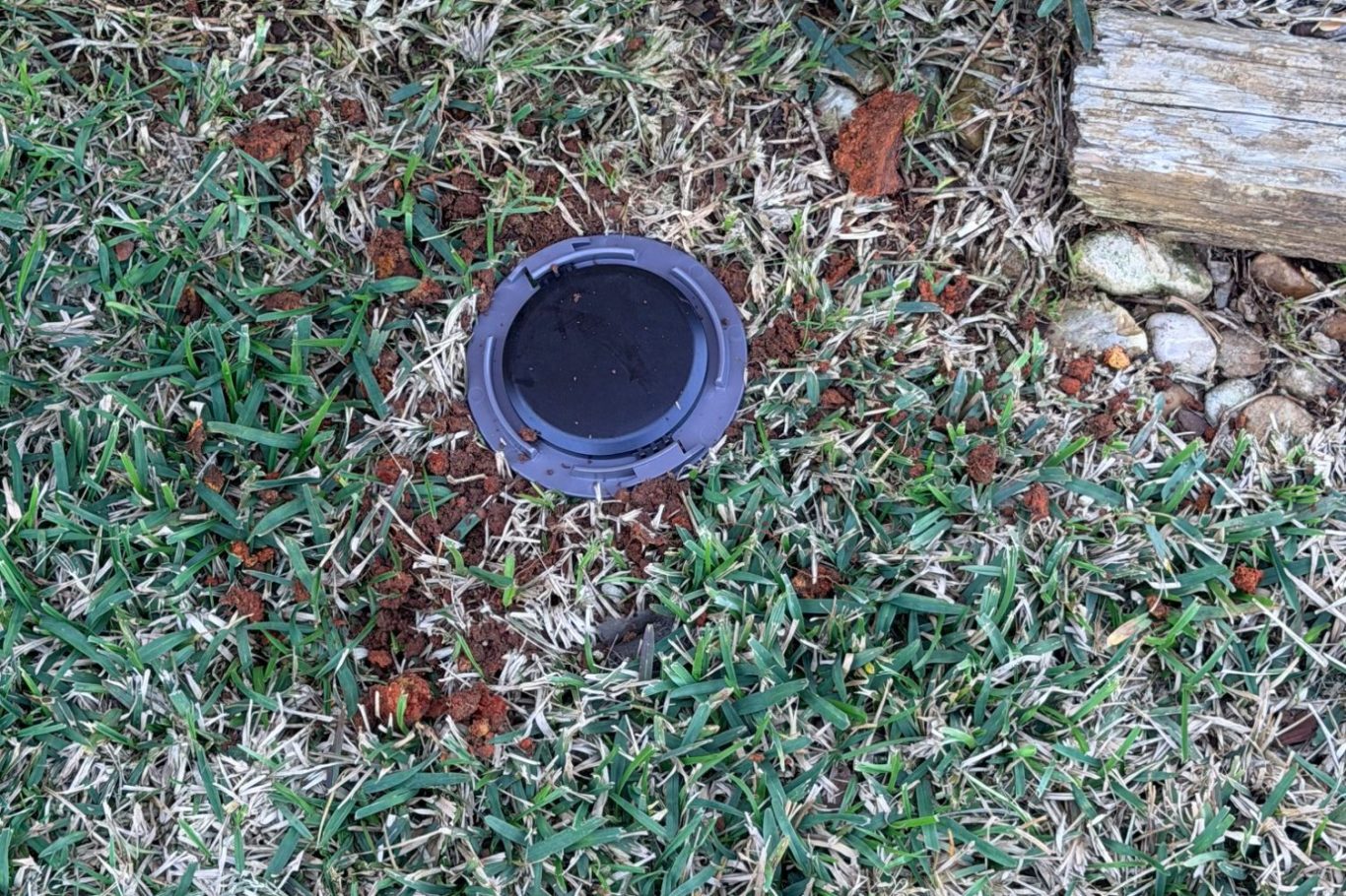 Termite bait station installed in soil near home foundation for termite control in Daphne, Alabama