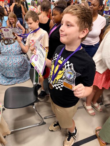 Isaac Celebrates Fourth Grade Graduation Isaac holding his certificate and award during his fourth grade graduation ceremony.