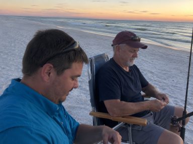Steve Hilbun and His Father Fishing at Fort Morgan Beach Steve Hilbun and his father sitting on Fort Morgan Beach, Alabama, preparing fishing gear at sunset.
