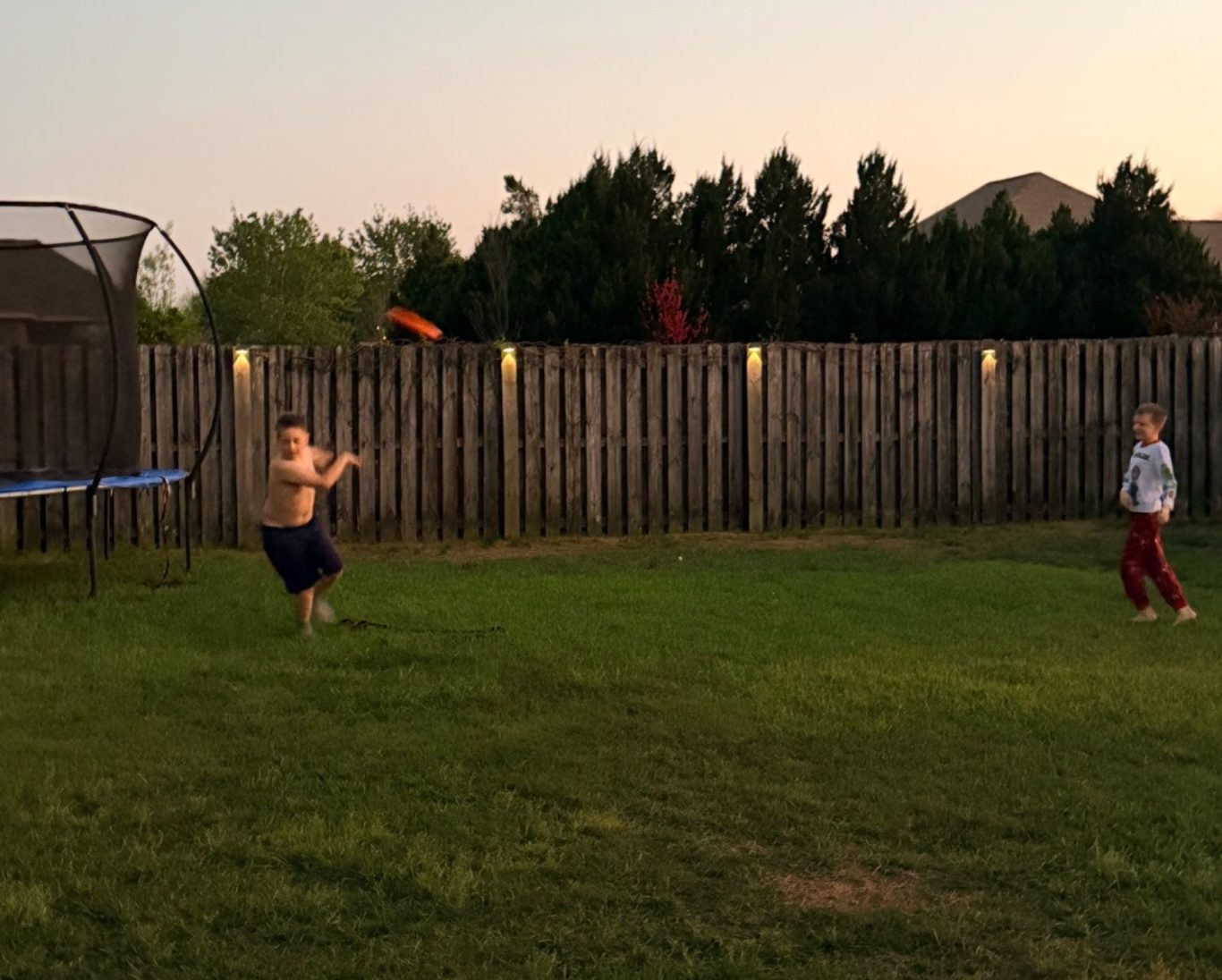 Two kids playing frisbee in a backyard protected by mosquito control Fairhope AL