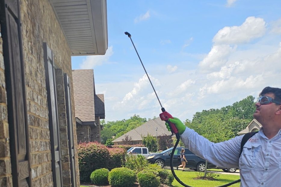 Exterior Pest Control Treatment in Daphne, Alabama | Hilbun Pest Control Hilbun Pest Control technician applying an exterior perimeter pest treatment beneath the eaves of a home in Daphne, Alabama.