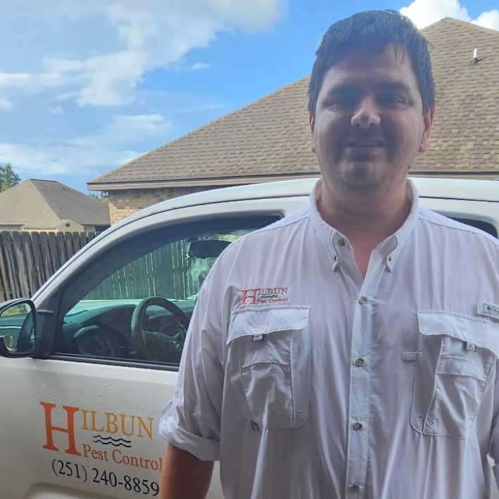 Hilbun Pest Services rodent control technician smiling next to service truck at a Daphne Alabama home
