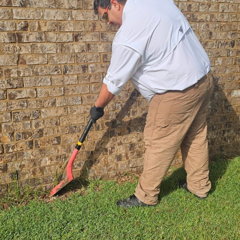 A termite tech is performing an inspection of the soil out side of a home in Fairhope, AL